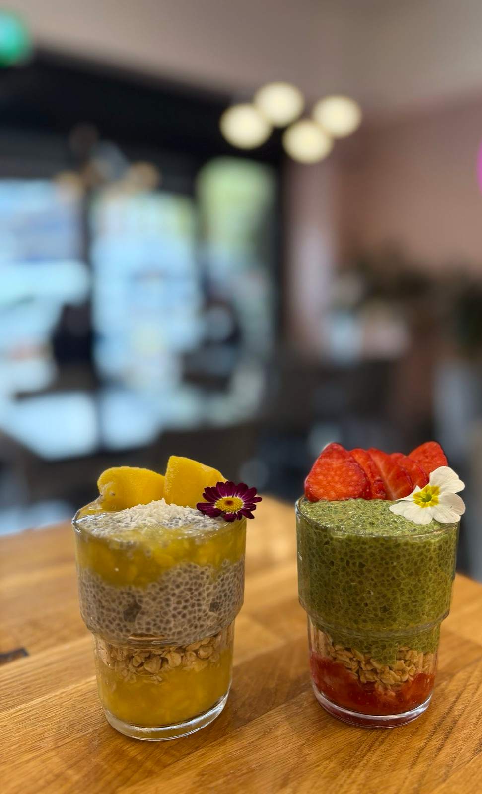 Two layered fruit, granola and chia parfaits topped with fresh fruit and flowers